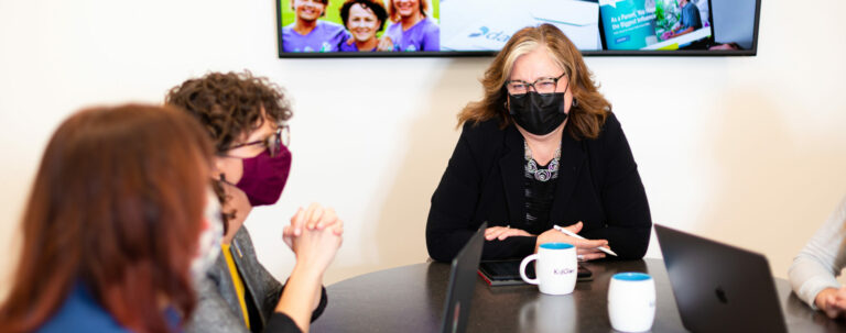 three women sitting at a table wearing kn95 masks discussing branding