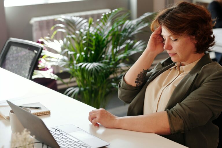 A healthcare marketing employee feeling stressed about their painpoints as they sit at a desk