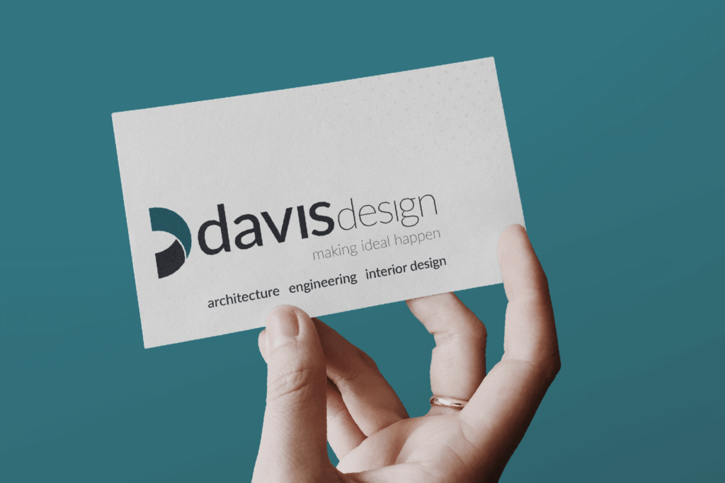 Image of a hand holding a Davis Design business card on a teal background.